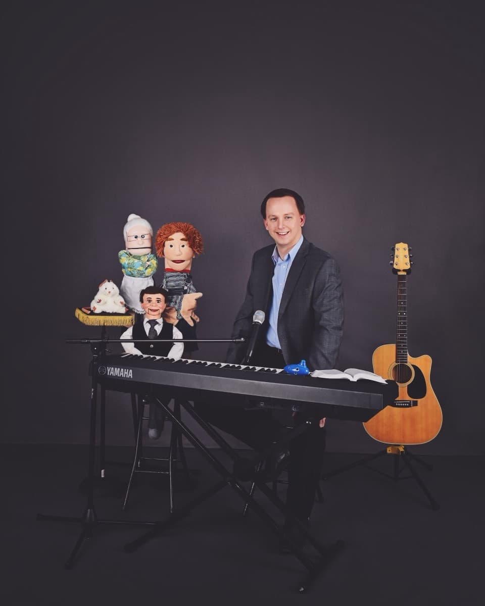 Stephen Forester at the keyboard with three of his puppets and his guitar