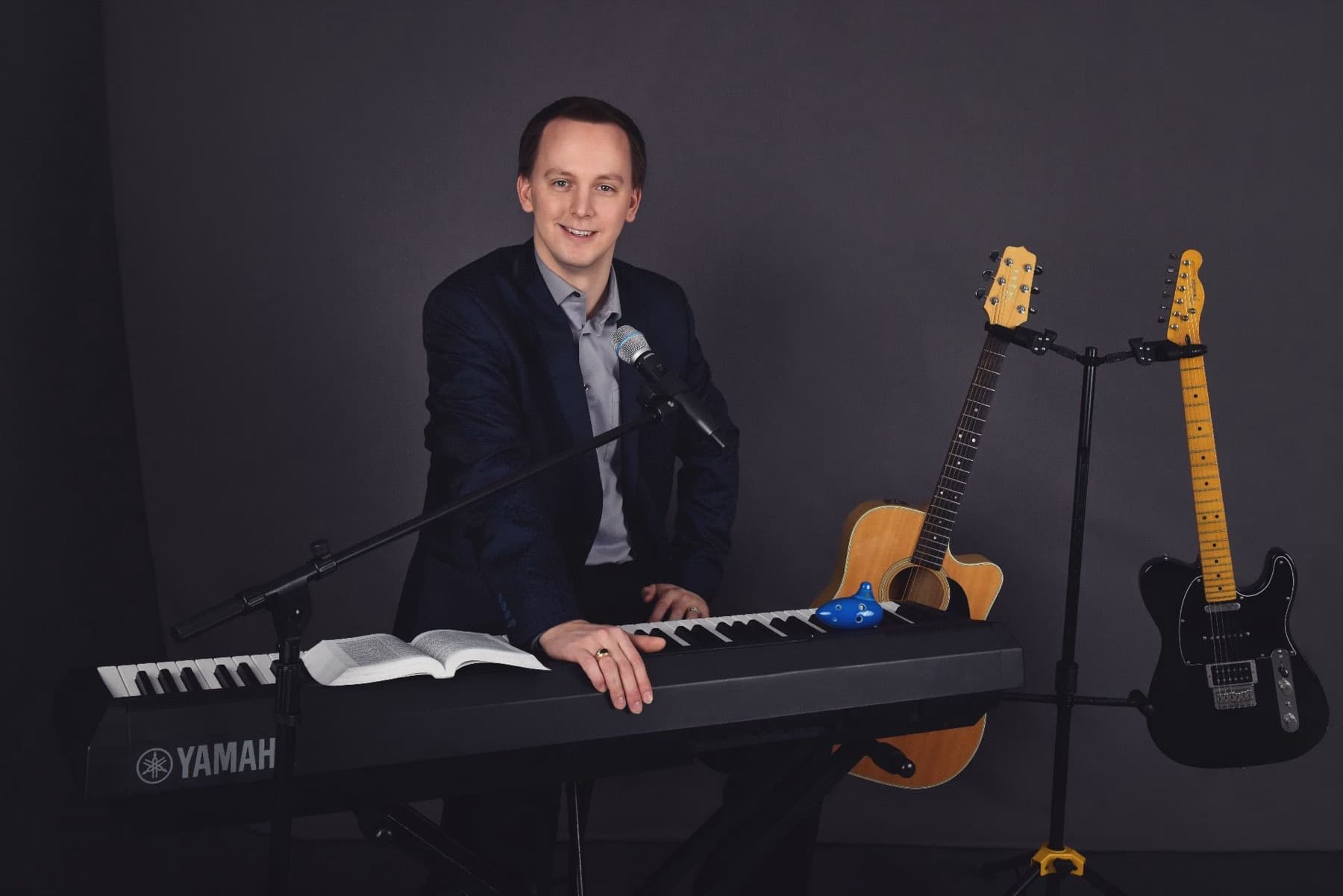 Stephen Forester at the keyboard with guitars and Bible